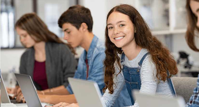 Smiling girl working on computer in classroom